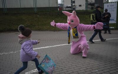 Performer Ben Dusing, from Fort Mitchell, Kentucky, US, wears an Easter rabbit costume as he prepares to embrace Lilia at the Medyka border crossing in Poland on April 17, 2022. (AP Photo/Rodrigo Abd)