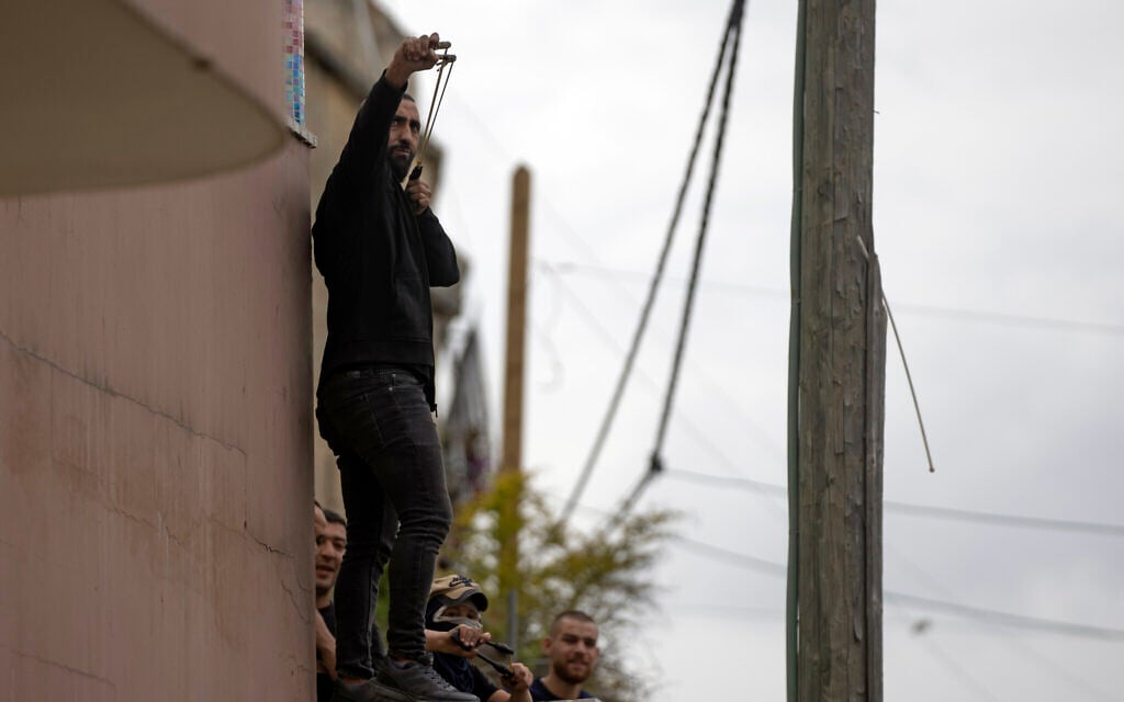 Palestinian protesters use slingshots during clashes with Israeli border police in the West Bank village of Burqa, north of Nablus, Tuesday, April 19, 2022. (AP/Nasser Nasser)