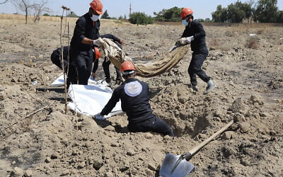 This frame grab from video shows Syrian workers of the Civil Council of Raqqa digging for human remains at the site of a mass grave believed to contain the bodies of civilians and Islamic State militants, in Raqqa, Syria, on July 14, 2019. (AP Photo, File)