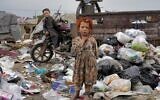 Two Afghan children stand amid piles of garbage next to their home, in Kabul, Afghanistan, April 18, 2022. (AP Photo/Ebrahim Noroozi)