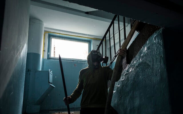 A man wearing a gas mask helps firefighters extinguish a fire on a residential building following a Russian bombardment in Kharkiv, Ukraine, on Thursday, April 21, 2022. (AP Photo/Felipe Dana) A man wearing a gas mask helps firefighters extinguish a fire on a residential building following a Russian bombardment in Kharkiv, Ukraine, on Thursday, April 21, 2022. (AP Photo/Felipe Dana)