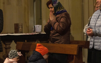 A Ukrainian woman prays during an orthodox Easter service for Ukrainians, both residents and refugees, in Melzo, in the outskirts of Milan, on April 23, 2022. (AP Photo/Alberto Pellaschiar)