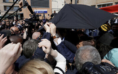 French President Emmanuel Macron is protected by an umbrella after a projectile was thrown during a walkabout at the Saint-Christophe market square in Cergy, a Paris suburb, April 27, 2022. (Benoit Tessier, Pool via AP)