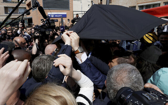 French President Emmanuel Macron is protected with an umbrella after a projectile was thrown during a walkabout at the Saint-Christophe market square in Cergy, a Paris suburb, April 27, 2022. (Benoit Tessier, Pool via AP) French President Emmanuel Macron is protected with an umbrella after a projectile was thrown during a walkabout at the Saint-Christophe market square in Cergy, a Paris suburb, April 27, 2022. (Benoit Tessier, Pool via AP)
