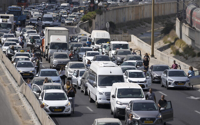 Israelis stand still next to their cars on a freeway as a two-minute siren sounds in memory of victims of the Holocaust in Tel Aviv, Israel, April 28, 2022 (AP Photo/Ariel Schalit)