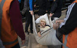 Klavidia, 91, is carried on an improvised stretcher as she boards a train, fleeing the fighting in Severodonetsk at a train station in Pokrovsk, Ukraine, on April 25, 2022. (AP Photo/Leo Correa)