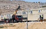 Israeli security forces use a crane to remove illegally built modular homes as they evacuate settlers in the Beit Dror outpost, in the hills south of the West Bank city of Hebron, July 27, 2021. (Wisam Hashlamoun/Flash90)