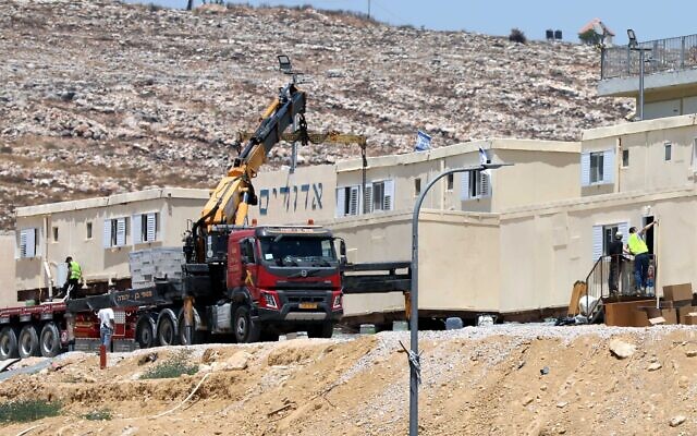 Israeli security forces use a crane to remove illegally built modular homes as they evacuate settlers in the Beit Dror outpost, in the hills south of the West Bank city of Hebron, July 27, 2021. (Wisam Hashlamoun/Flash90) Israeli security forces use a crane to remove illegally built modular homes as they evacuate settlers in the Beit Dror outpost, in the hills south of the West Bank city of Hebron, July 27, 2021. (Wisam Hashlamoun/Flash90)