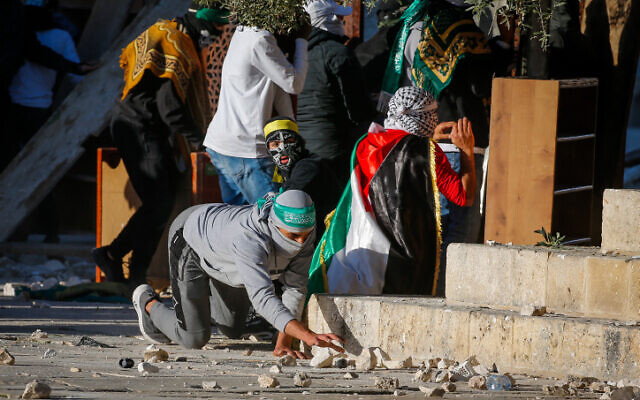 A Palestinian protester picks up a stone during clashes with Israeli police on the Temple Mount in Jerusalem's Old City on April 15, 2022. (Jamal Awad/Flash90) A Palestinian protester picks up a stone during clashes with Israeli police on the Temple Mount in Jerusalem's Old City on April 15, 2022. (Jamal Awad/Flash90)