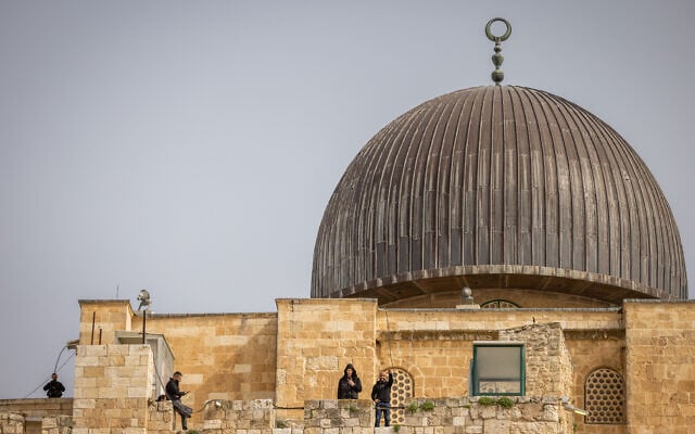 Palestinians flash victory signs beneath the dome of the Al-Aqsa Mosque, on the Temple Mount in Jerusalem's Old City, on April 17, 2022. (Yonatan Sindel/Flash90)