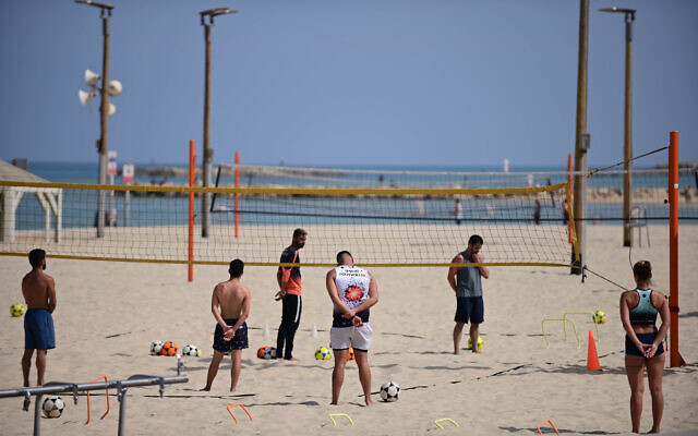 Israelis stand still on the beach in Tel Aviv, as a two-minute siren is sounded across Israel to mark Holocaust Remembrance Day on April 28, 2022 (Tomer Neuberg/Flash90)