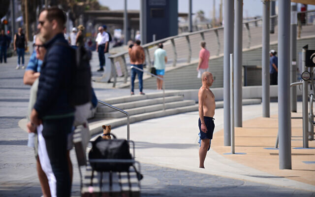 Israelis stand still on the beach in Tel Aviv, as a two-minute siren is sounded across Israel to mark Holocaust Remembrance Day on April 28, 2022 (Tomer Neuberg/Flash90)