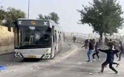 Palestinians throw rocks at an Israeli bus outside Jerusalem's Old City on April 17, 2022. (Screen capture: Twitter)