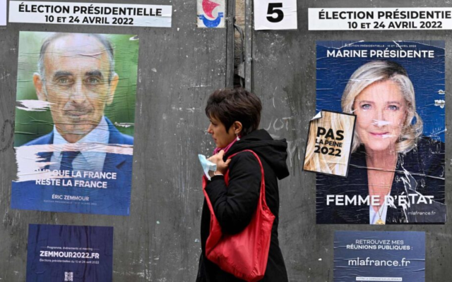 A pedestrian walks past campaign posters for French presidential candidates Eric Zemmour, left, and Marine Le Pen ahead of the first round of the French presidential election in Paris, on April 7, 2022. (Emmanuel Dunand/AFP/Getty Images via JTA)