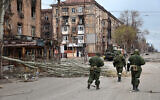 Pro-Russia troops from the Donetsk People's Republic militia walk past damaged apartment buildings near the Illich Iron & Steel Works Metallurgical Plant in an area controlled by Russian-backed separatist forces in Mariupol, Ukraine, April 16, 2022. (AP Photo/Alexei Alexandrov)