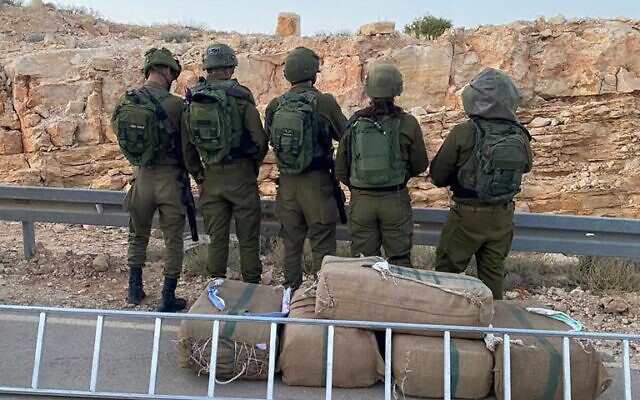 Troops stand next to drugs seized during a smuggling attempt on the Egypt border, on April 23, 2022. (Israel Defense Forces) Troops stand next to drugs seized during a smuggling attempt on the Egypt border, on April 23, 2022. (Israel Defense Forces)