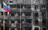 A Russian national flag flies by destroyed buildings in Mariupol on April 12, 2022, as Russian troops intensify a campaign to take the strategic port city. *EDITOR'S NOTE: This picture was taken during a trip organized by the Russian military.* (Photo by Alexander NEMENOV / AFP)
