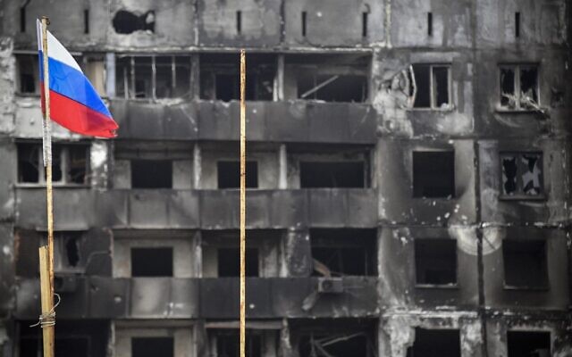 A Russian national flag flies by destroyed buildings in Mariupol on April 12, 2022, as Russian troops intensify a campaign to take the strategic port city. *EDITOR'S NOTE: This picture was taken during a trip organized by the Russian military.* (Photo by Alexander NEMENOV / AFP) A Russian national flag flies by destroyed buildings in Mariupol on April 12, 2022, as Russian troops intensify a campaign to take the strategic port city. *EDITOR'S NOTE: This picture was taken during a trip organized by the Russian military.* (Photo by Alexander NEMENOV / AFP)