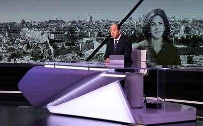 Al Jazeera's Abdel Samad Nasser broadcasts a report before an image of his network colleague Shireen Abu Akleh at the Qatari news broadcaster's main headquarters in the capital Doha on May 11, 2022. Abu Akleh was shot dead during clashes between Israeli troops and Palestinian gunmen as she covered an IDF raid on the West Bank's Jenin refugee camp earlier in the day. (Karim Jaafar / AFP)