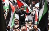 Illustrative: Palestinians wave national flags as they march in a rally marking the 74th anniversary of the 'Nakba' or 'catastrophe' of Israel's founding in the West Bank town of Ramallah, on May 15, 2022. (ABBAS MOMANI/AFP)
