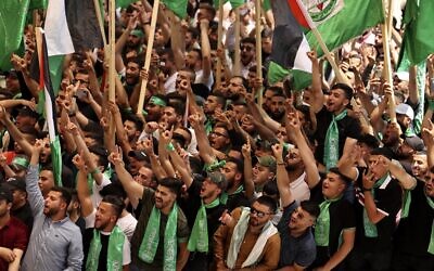 Palestinian students supporting the Hamas terror group wave flags as they attend a debate ahead of student council elections at Birzeit University on the outskirts of Ramallah in the West Bank, on May 17, 2022. (Abbas Momani/AFP)