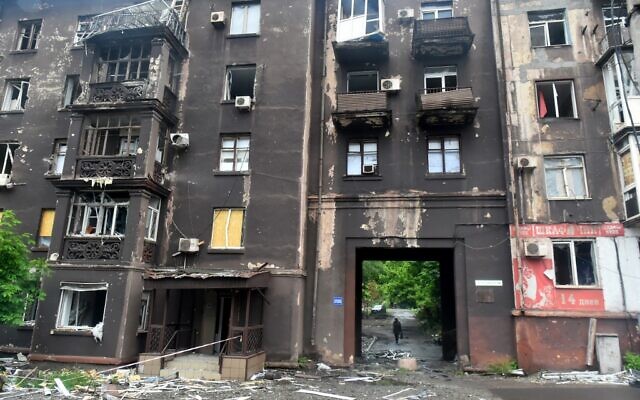 A woman walks behind a burnt residential building in Ukraine's port city of Mariupol on May 18, 2022. (Olga MALTSEVA / AFP) A woman walks behind a burnt residential building in Ukraine's port city of Mariupol on May 18, 2022. (Olga MALTSEVA / AFP)