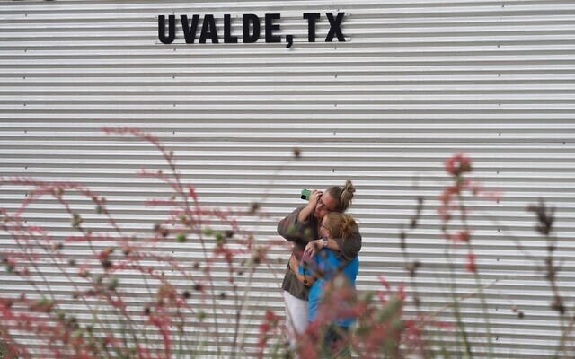 A woman cries and hugs a young girl while on the phone outside the Willie de Leon Civic Center where grief counseling will be offered in Uvalde, Texas, on May 24, 2022. (Allison Dinner / AFP)