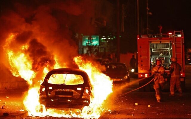 Firefighters extinguish a vehicle set aflame during clashes in the East Jerusalem neighborhood of Sheikh Jarrah on May 29, 2022, after the Israeli Flag March to mark Jerusalem Day. (Photo by RONALDO SCHEMIDT / AFP) Firefighters extinguish a vehicle set aflame during clashes in the East Jerusalem neighborhood of Sheikh Jarrah on May 29, 2022, after the Israeli Flag March to mark Jerusalem Day. (Photo by RONALDO SCHEMIDT / AFP)