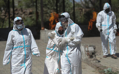A relative of a person who died of COVID-19 is consoled by another during cremation in Jammu, India, on April 25, 2021. (AP Photo/Channi Anand, File)