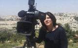 In this undated photo provided by Al Jazeera Media Network, Shireen Abu Akleh, a journalist for Al Jazeera network, stands next to a TV camera with the Old City of Jerusalem in the background. (Al Jazeera Media Network via AP)