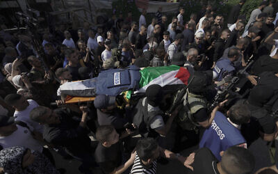 Palestinian militants carry the body of Shireen Abu Akleh, a journalist for Al Jazeera network, into the morgue inside the Hospital in the West Bank town of Jenin, May 11, 2022. (AP Photo/Majdi Mohammed)