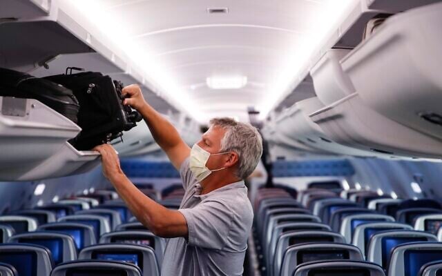 In this May 28, 2020, file photo, a passenger wears personal protective equipment on a Delta Airlines flight after landing in Minneapolis, Minnesota (AP Photo/John Minchillo, File) In this May 28, 2020, file photo, a passenger wears personal protective equipment on a Delta Airlines flight after landing in Minneapolis, Minnesota (AP Photo/John Minchillo, File)