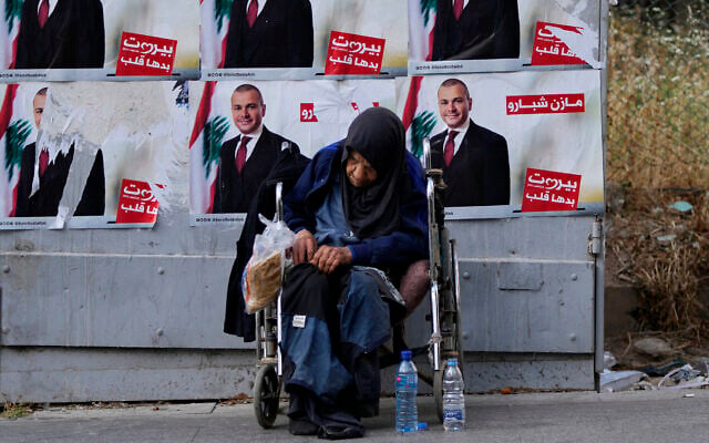 A homeless woman sits in front of campaign posters for a candidate in the upcoming parliamentary elections in Beirut, Lebanon, May 9, 2022. (AP Photo/Hassan Ammar) A homeless woman sits in front of campaign posters for a candidate in the upcoming parliamentary elections in Beirut, Lebanon, May 9, 2022. (AP Photo/Hassan Ammar)