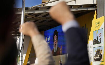 Hezbollah supporters raise their fists and cheer, as they listens to a speech by Hezbollah leader Sayyed Hassan Nasrallah through a giant screen during an election campaign, in the southern suburb of Beirut, Lebanon, May 10, 2022. (AP Photo/Hussein Malla)