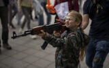 Victoria, 7, uses a plastic Kalashnikov rifle to shoot balls at a portrait of Russian President Vladimir Putin, at a street attraction in the center of Lviv, Ukraine, on May 14, 2022. (Emilio Morenatti/AP)