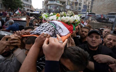 Palestinian mourners carry the body of veteran Palestinian-American reporter Shireen Abu Akleh out of the office of Al Jazeera after friends and colleagues paid their respects, in the West Bank city of Ramallah, May 11, 2022. (AP/Nasser Nasser, File)