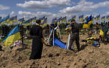 Undertakers lower the coffin of Ukrainian serviceman Oleksander Matyukhin, 32, in Kharkiv, eastern Ukraine, May 23, 2022. (AP Photo/Bernat Armangue)