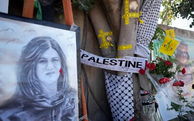 Yellow tape marks bullet holes on a tree and a portrait and flowers create a makeshift memorial at the site where Palestinian-American Al-Jazeera journalist Shireen Abu Akleh was shot and killed in the West Bank city of Jenin, on May 19, 2022. (AP/Majdi Mohammed)