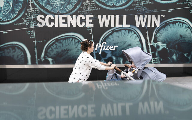 A woman pushes a baby in a stroller past a sign hanging outside Pfizer headquarters in New York, May 23, 2022. (Mary Altaffer/AP) A woman pushes a baby in a stroller past a sign hanging outside Pfizer headquarters in New York, May 23, 2022. (Mary Altaffer/AP)