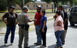 A policeman talks to people asking for information outside of the Robb Elementary School in Uvalde, Texas, May 24, 2022. An 18-year-old gunman opened fire at the Texas elementary school, killing multiple people.  AP Photo/Dario Lopez-Mills)