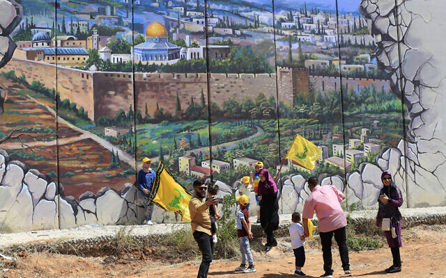 Hezbollah supporters wave flags in front of a poster showing the Dome of the Rock and the Al Aqsa Mosque on the Temple Mount painted on an Israeli built border wall as they mark the twenty second anniversary of Israel's withdrawal from southern Lebanon in May 25, 2000, in Kfar Kila village, Southern Lebanon, Wednesday, May 25, 2022. (AP Photo/Mohammed Zaatari) Hezbollah supporters wave flags in front of a poster showing the Dome of the Rock and the Al Aqsa Mosque on the Temple Mount painted on an Israeli built border wall as they mark the twenty second anniversary of Israel's withdrawal from southern Lebanon in May 25, 2000, in Kfar Kila village, Southern Lebanon, Wednesday, May 25, 2022. (AP Photo/Mohammed Zaatari)
