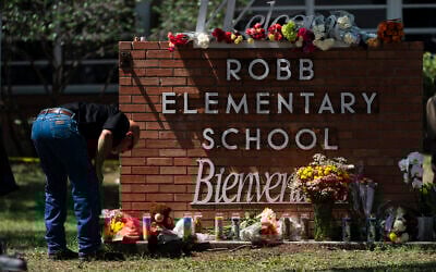 A law enforcement officer lights a candle outside Robb Elementary School in Uvalde, Texas, Wednesday, May 25, 2022. (AP/Jae C. Hong)
