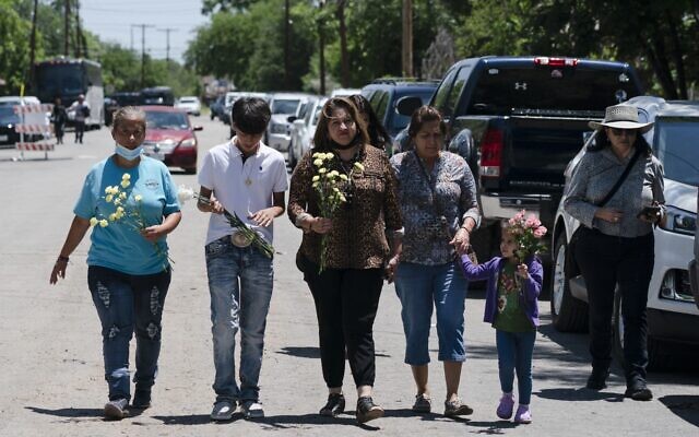 People walk with flowers to honor the victims in Tuesday's shooting at Robb Elementary School in Uvalde, Texas, Wednesday, May 25, 2022 (AP Photo/Jae C. Hong) People walk with flowers to honor the victims in Tuesday's shooting at Robb Elementary School in Uvalde, Texas, Wednesday, May 25, 2022 (AP Photo/Jae C. Hong)