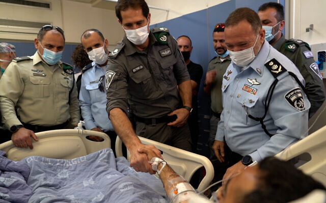 Police chief Kobi Shabtai and Border Police chief Amir Cohen visit first sergeant M at the Hadassah hospital in Jerusalem after he was stabbed by a Palestinian assailant at Jerusalem's Damascus Gate, on May 9, 2022. (Israel Police)