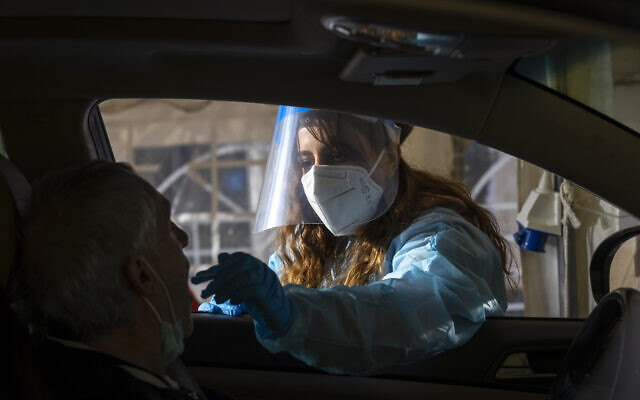 A Magen David Adom health worker take a swab sample from at a drive-thru COVID-19 testing complex in Jerusalem, on March 22, 2022. (Olivier Fitoussi/Flash90) A Magen David Adom health worker take a swab sample from at a drive-thru COVID-19 testing complex in Jerusalem, on March 22, 2022. (Olivier Fitoussi/Flash90)