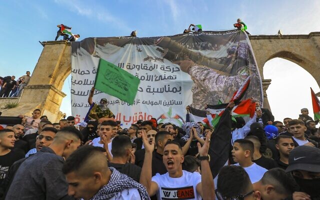 Palestinians chant pro-Hamas slogans following Eid al-Fitr prayers in front of a banner supporting the terror group at the Al-Aqsa Mosque atop the Temple Mount in Jerusalem on May 2, 2022. (Jamal Awad/Flash90