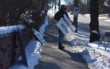 A protester stands outside Beth Israel Congregation in Ann Arbor, Michigan, flanked by anti-Israel and antisemitic signs, in 2020. On Jan. 18, 2022, the Ann Arbor City Council formally condemned the weekly protests, which had been going on for 18 years. (Alex Sherman/Jewish Telegraphic Agency)