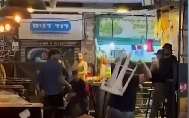 People fighting at Jerusalem's Mahane Yehuda market with chairs and tables, May 15, 2022. (screenshot). People fighting at Jerusalem's Mahane Yehuda market with chairs and tables, May 15, 2022. (screenshot).