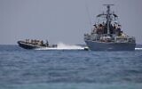People sail past an Israeli navy vessel off the coast of Rosh Hanikra, an area at the border between Israel and Lebanon (Ras al-Naqura), on June 6, 2022. (JALAA MAREY / AFP)