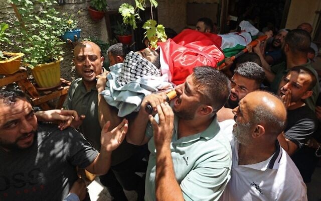 Mourners carry the body of Ali Harb, who was allegedly stabbed to death by an Israeli settler, during his funeral in the northern West Bank village of Iskaka on June 22, 2022. (JAAFAR ASHTIYEH / AFP) Mourners carry the body of Ali Harb, who was allegedly stabbed to death by an Israeli settler, during his funeral in the northern West Bank village of Iskaka on June 22, 2022. (JAAFAR ASHTIYEH / AFP)